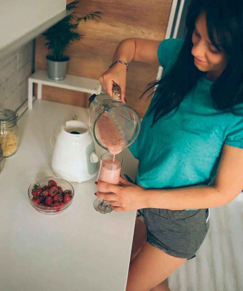 Chica prepara un batido de fresas en licuadora