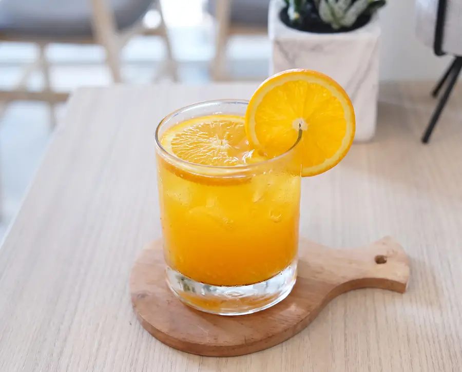 Vaso de jugo de naranja natural con hielo y rodaja de naranja