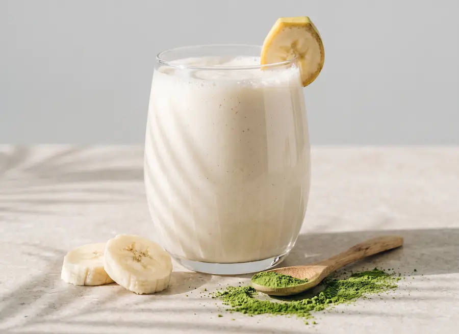 Vaso de vidrio con licuado de plátano espeso y cremoso